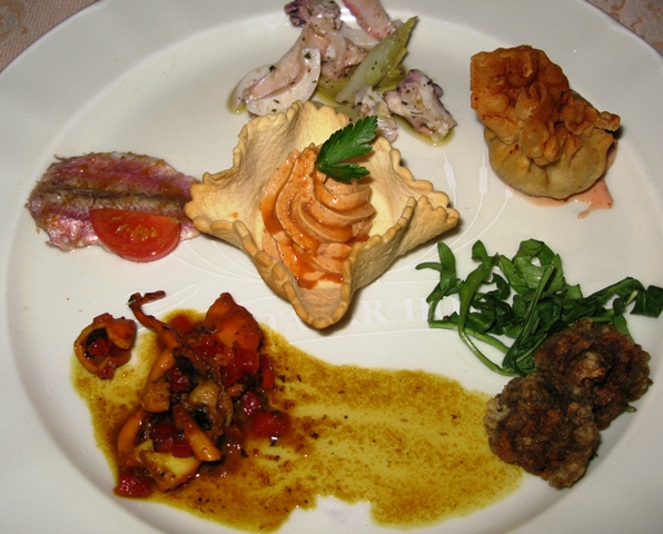 il composito antipasto, al centro la mousse di ricci in cialda alla vernaccia, trigliette marinate, insalatina di moscardini, fagottino di orata e ricci e soprattutto orziadas fritte